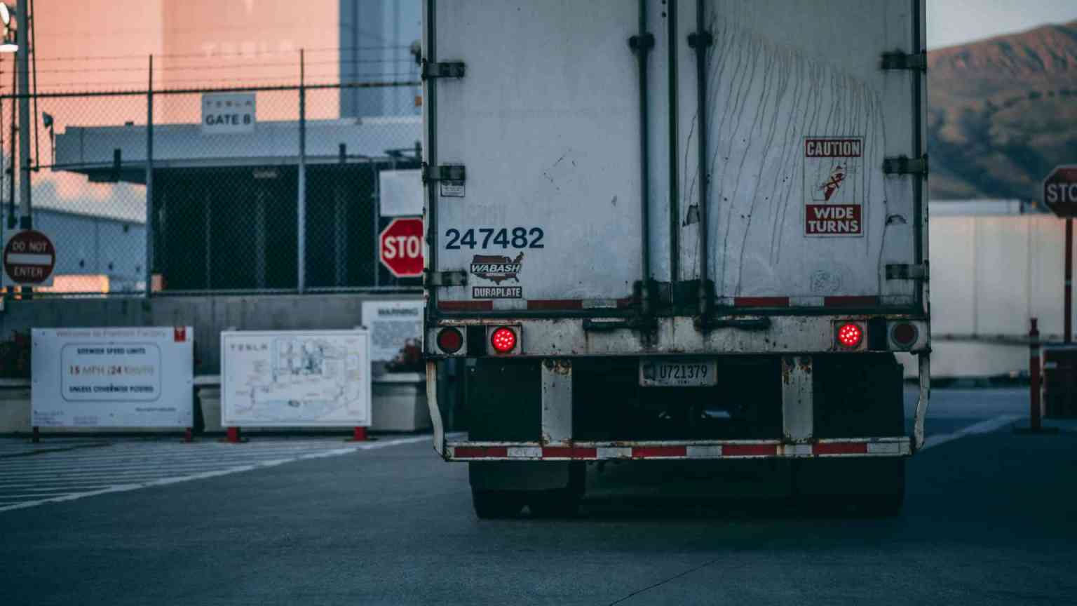 Back view of semi truck driving to facility